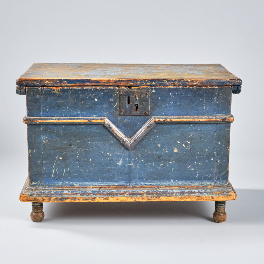 A small, child's size V pine blanket box in old blue paint. Small bun feet. Quebec, circa 1820. 