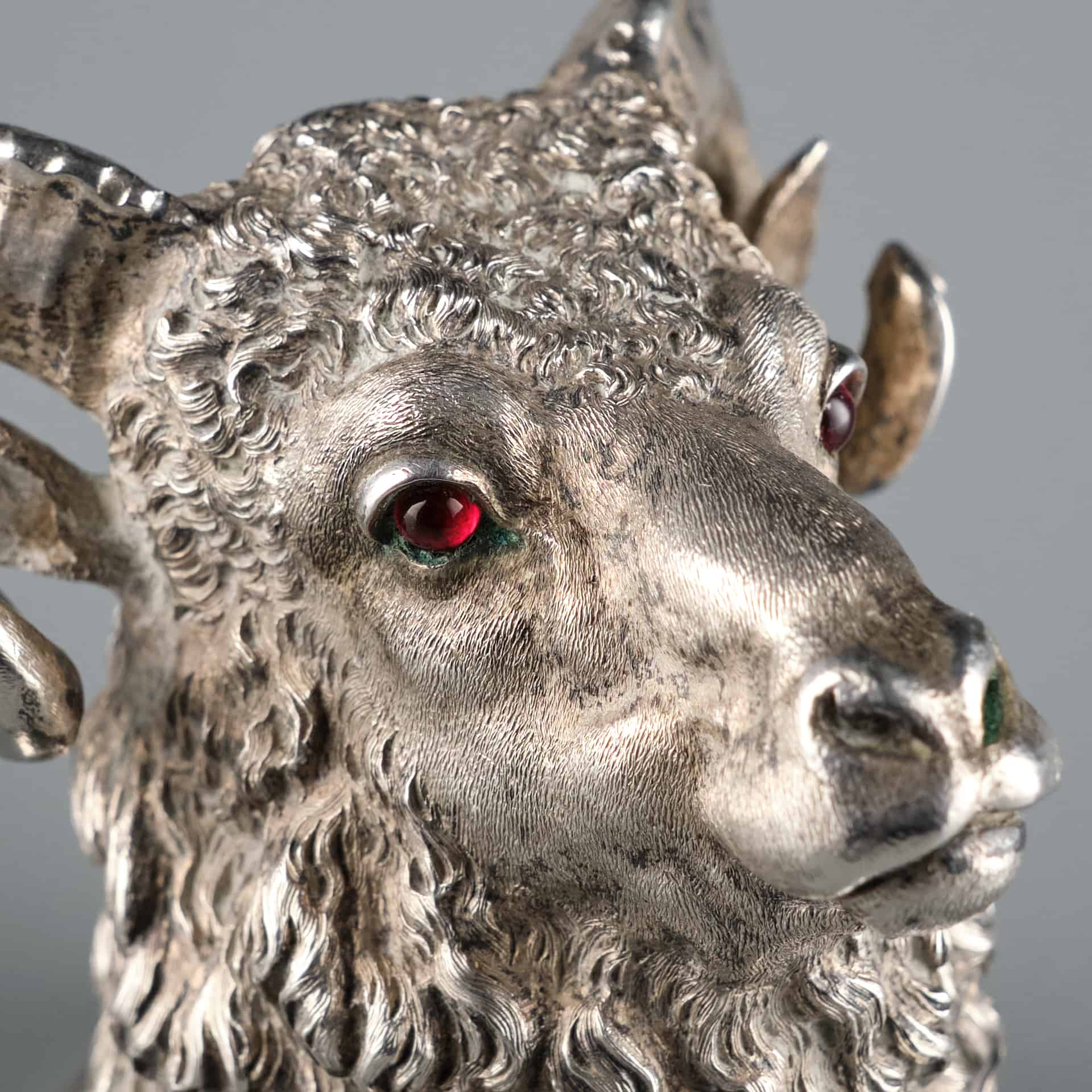 Showing a very fine Russian silver stirrup cup in the form of a Ram's head. The silver is beautifully casted to detail the Ram's face, horns, and mane. The ram's eyes are set by two bright red ruby gemstones.
