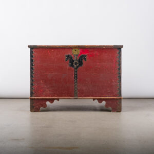A large and rare Ukrainian storage box from Sarto, Manitoba, in red and black paint, embellished with tin cutouts that are both decorative and functional, with original brass lock and decorative tacks.